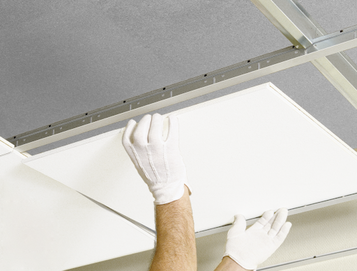 A ceiling tile being removed for re-use.