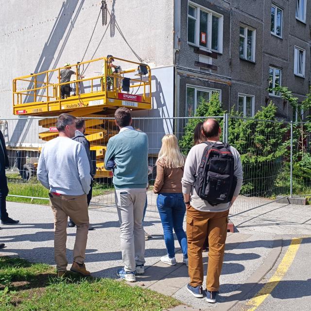 Group of people standing in front of a European building being renovated. 